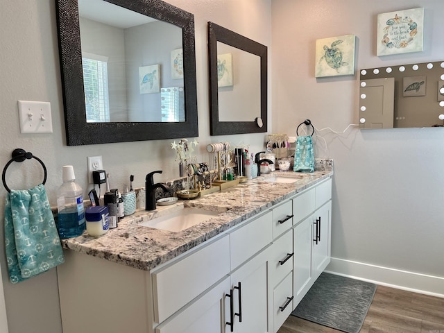 full bath with a sink, baseboards, double vanity, and wood finished floors