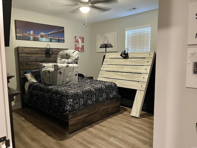 bedroom featuring a ceiling fan, visible vents, and wood finished floors