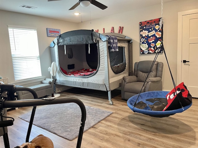 bedroom with ceiling fan, wood finished floors, and visible vents
