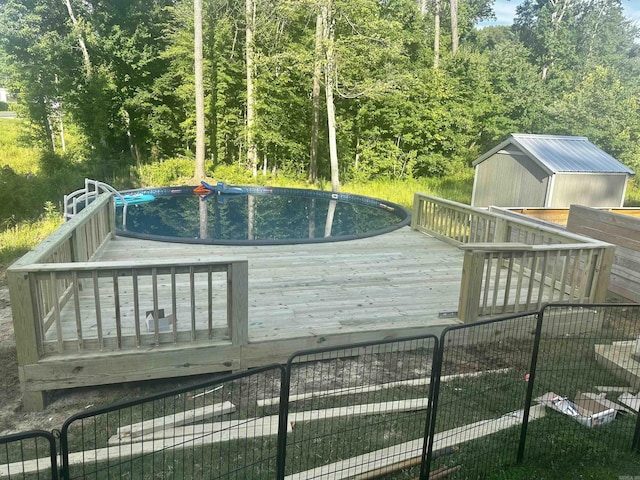 wooden terrace featuring a storage shed, an outdoor structure, and an outdoor pool