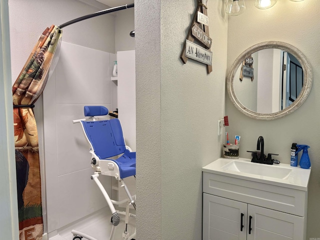 full bath with vanity, a textured wall, and a shower with curtain