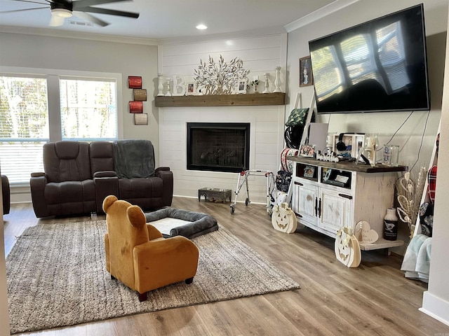 living area featuring a ceiling fan, ornamental molding, and wood finished floors