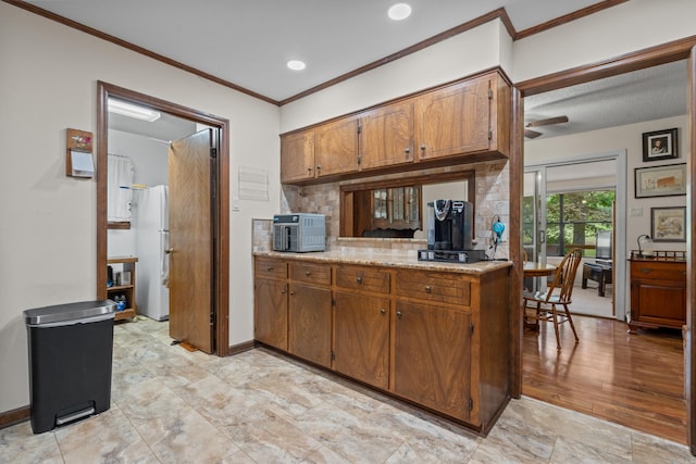 15 Tarifa Ln, Hot Springs Village, AR 71909 - kitchen with brown cabinetry, freestanding refrigerator, decorative backsplash, ornamental molding, and light countertops