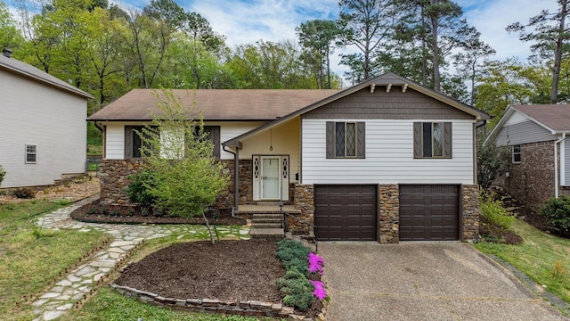 bi-level home with a garage, aphalt driveway, and stone siding
