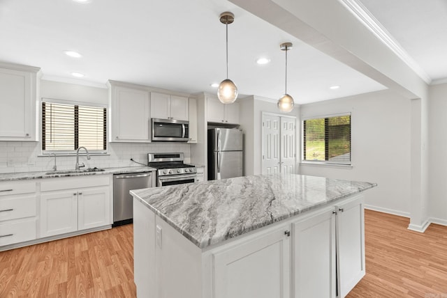 kitchen featuring appliances with stainless steel finishes, a center island, tasteful backsplash, a sink, and ornamental molding