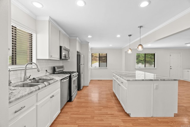 kitchen featuring appliances with stainless steel finishes, a sink, a center island, recessed lighting, and white cabinetry