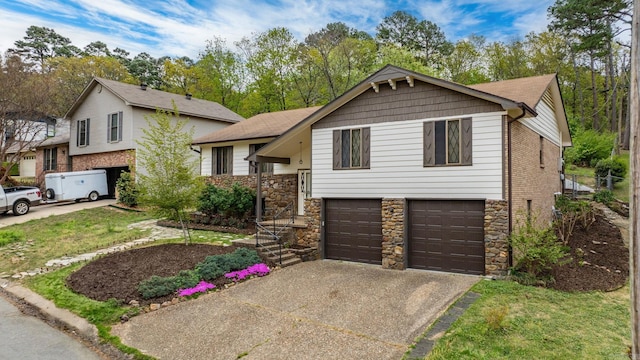tri-level home with concrete driveway, an attached garage, and stone siding