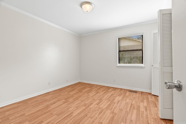 spare room featuring crown molding, baseboards, visible vents, and light wood-type flooring