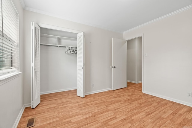 unfurnished bedroom with light wood-style floors, baseboards, ornamental molding, and a closet