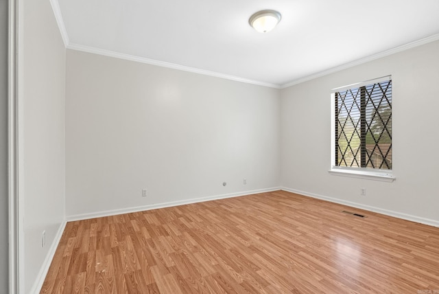 spare room featuring baseboards, visible vents, ornamental molding, and light wood-type flooring