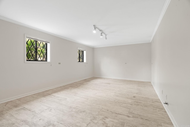 spare room with a healthy amount of sunlight, track lighting, ornamental molding, and baseboards