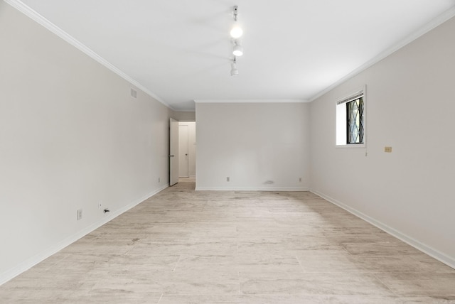 spare room featuring baseboards, ornamental molding, light wood-style flooring, and visible vents