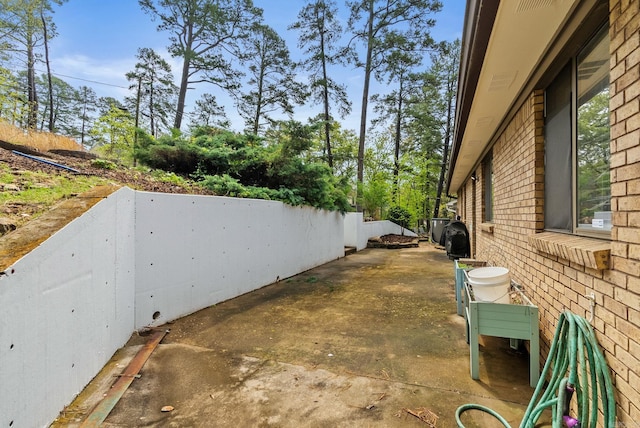 view of property exterior featuring brick siding and a patio