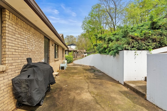 view of property exterior with brick siding, fence, and a patio