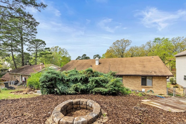 view of property exterior featuring fence, a chimney, an outdoor fire pit, and brick siding