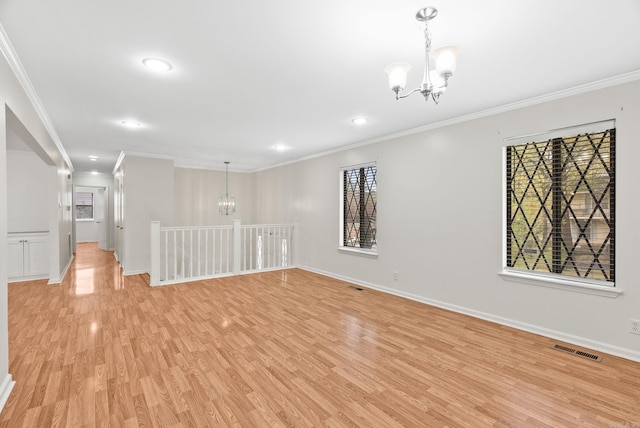 spare room with visible vents, ornamental molding, light wood-style flooring, and a chandelier