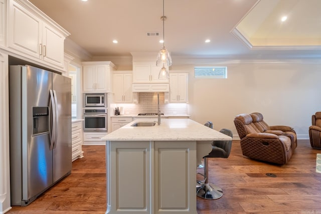 kitchen featuring backsplash, appliances with stainless steel finishes, a sink, white cabinets, and ornamental molding