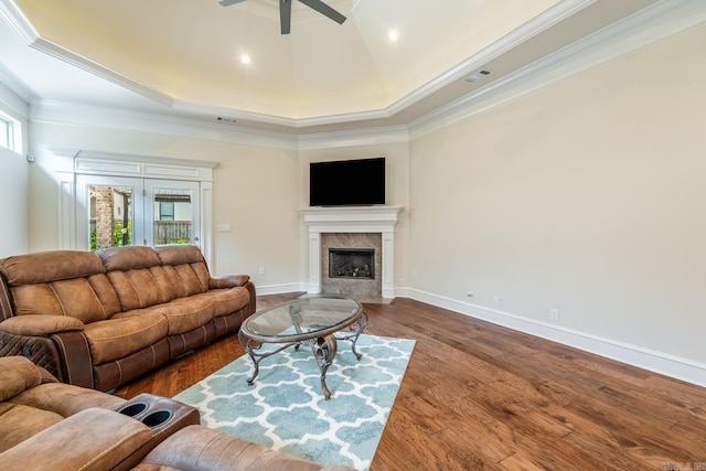 living area featuring ceiling fan, a fireplace, baseboards, wood finished floors, and ornamental molding
