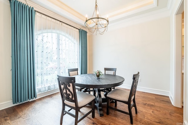 dining area featuring an inviting chandelier, ornamental molding, a tray ceiling, and wood finished floors
