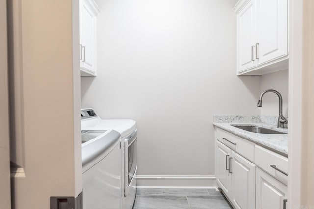 washroom featuring a sink, separate washer and dryer, baseboards, and cabinet space