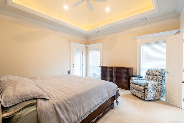 bedroom featuring ceiling fan, visible vents, crown molding, light colored carpet, and a tray ceiling