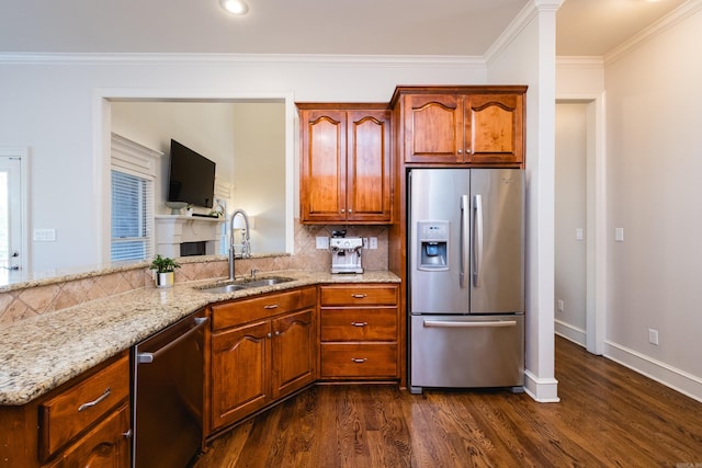 kitchen with appliances with stainless steel finishes, tasteful backsplash, a sink, light stone counters, and dark wood-type flooring