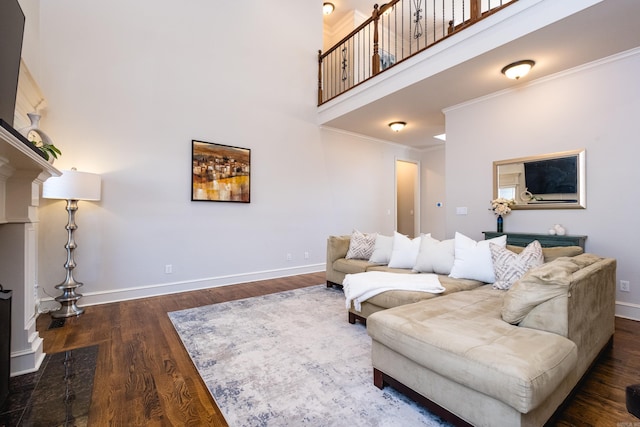 living area with baseboards, a high ceiling, crown molding, and wood finished floors