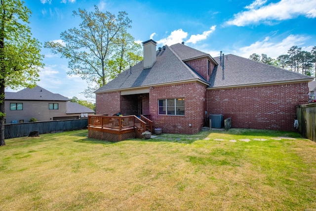rear view of property featuring a chimney, a wooden deck, brick siding, a fenced backyard, and a shingled roof