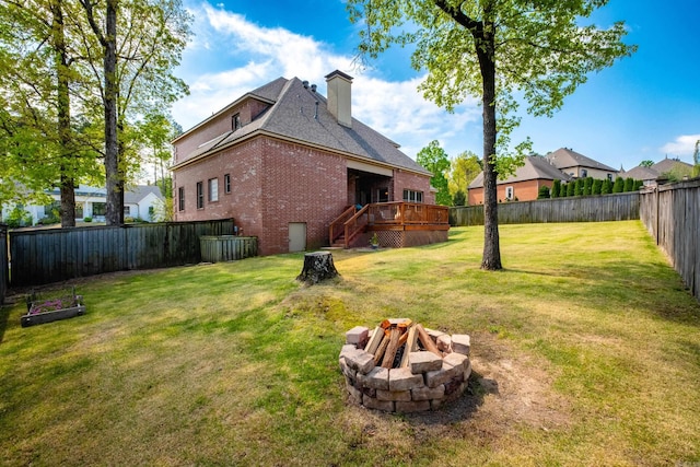 view of yard featuring stairway, a deck, a fenced backyard, and an outdoor fire pit