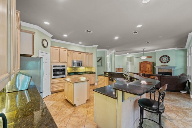 kitchen with crown molding, visible vents, a large island, a sink, and appliances with stainless steel finishes