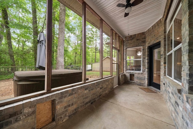unfurnished sunroom with a ceiling fan and a hot tub