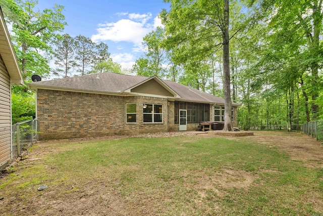 back of property featuring a fenced backyard, a lawn, a sunroom, and brick siding