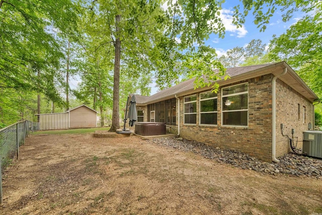 exterior space featuring central AC, a hot tub, and fence