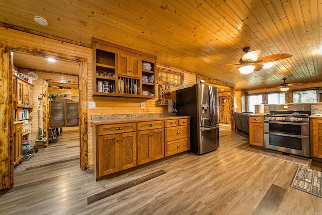 4 Long Hill Rd, Higden, AR 72067 - kitchen featuring brown cabinetry, wood walls, a ceiling fan, and stainless steel appliances