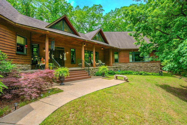 entrance to property featuring a yard, covered porch, and stone siding