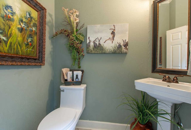 bathroom with baseboards and toilet