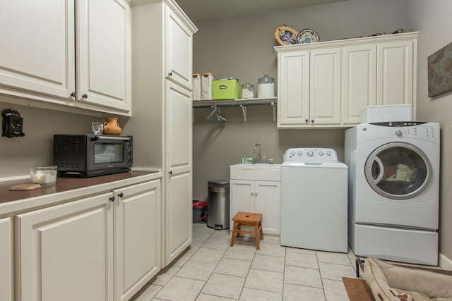 washroom featuring cabinet space, a sink, light tile patterned floors, a toaster, and washer and dryer