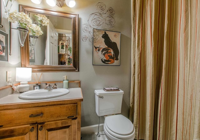 full bath featuring vanity, baseboards, a textured wall, and toilet