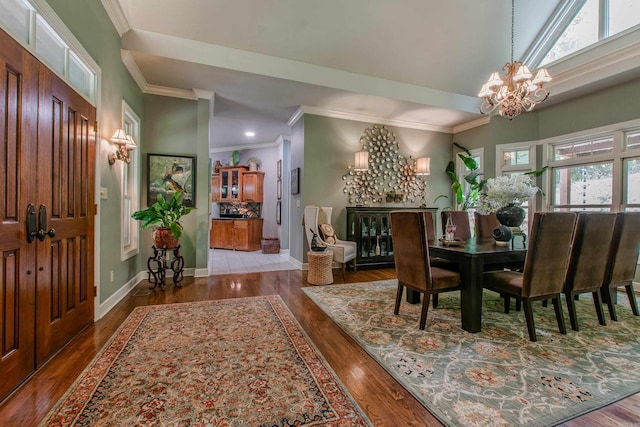 dining area featuring an inviting chandelier, ornamental molding, and wood finished floors