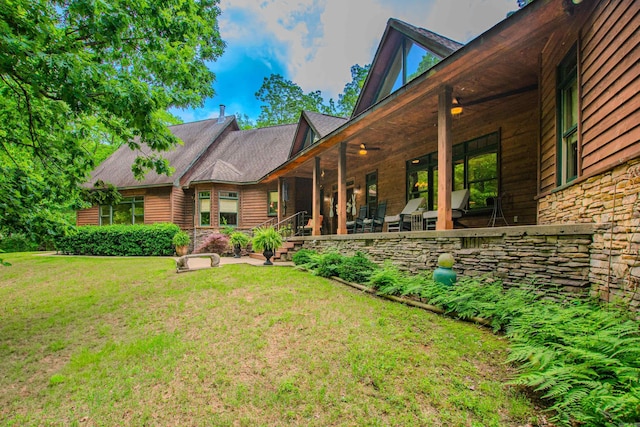 back of property with a yard and stone siding