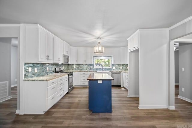 kitchen with decorative backsplash, a center island, white cabinets, a sink, and appliances with stainless steel finishes