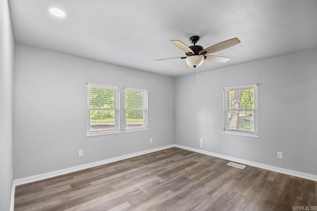 spare room with ceiling fan, baseboards, visible vents, and wood finished floors