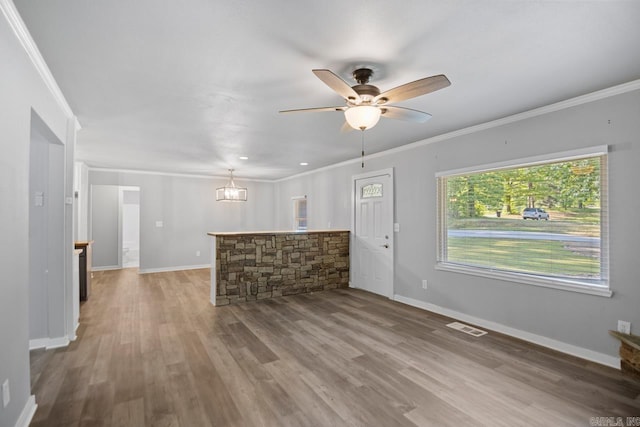 unfurnished living room with ceiling fan, visible vents, and ornamental molding