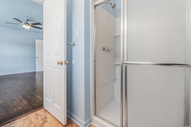 full bathroom featuring ceiling fan, baseboards, and a stall shower
