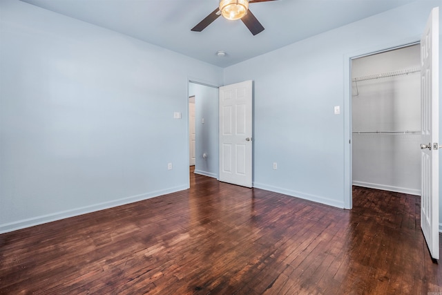 unfurnished bedroom with baseboards, wood-type flooring, a closet, and a spacious closet