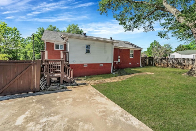 back of house with a fenced backyard, a patio, a yard, and brick siding