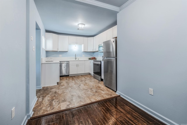 kitchen with a sink, baseboards, stainless steel appliances, and white cabinetry