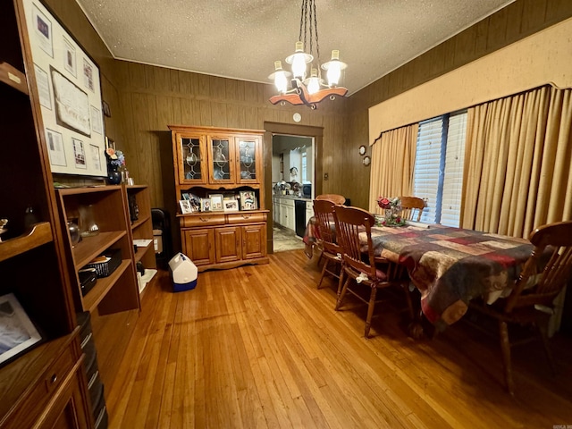 1519 S Oak St, Little Rock, AR 72204 - dining space with light wood-type flooring, wood walls, a textured ceiling, and a notable chandelier