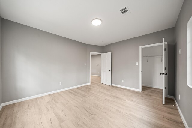 609 S St, Hot Springs, AR 71913 - unfurnished bedroom featuring baseboards, visible vents, a walk in closet, and light wood-style floors