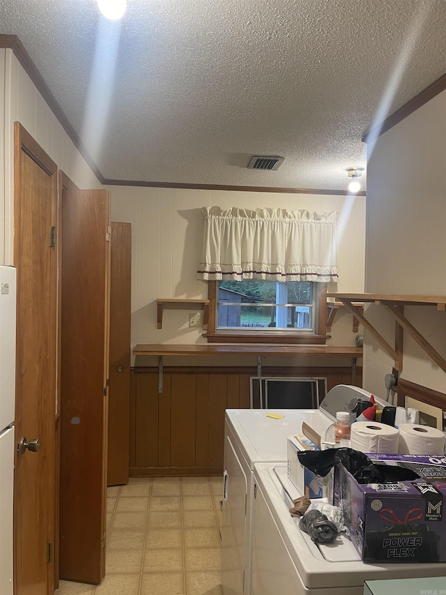 clothes washing area with a textured ceiling, ornamental molding, light floors, visible vents, and washing machine and dryer